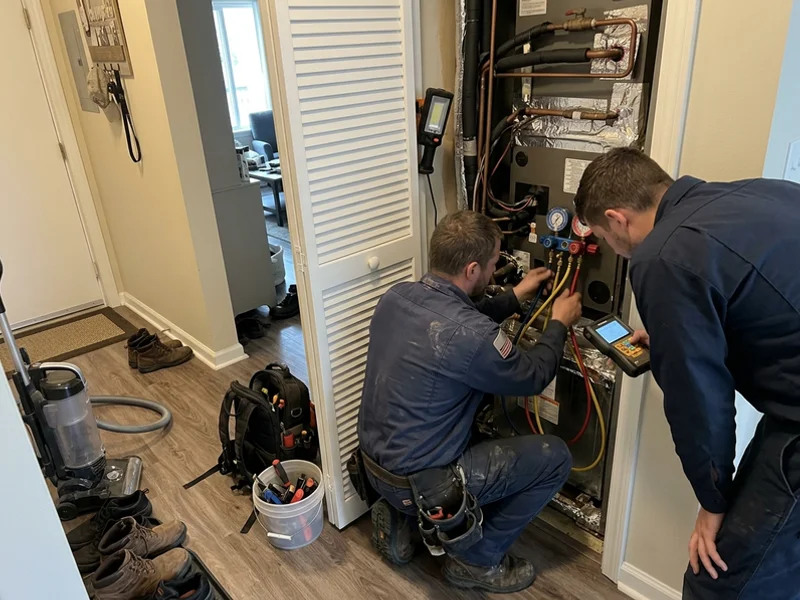 Technicians connecting refrigerant gauges to a condo air handler